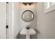 Modern powder room with pedestal sink, round mirror, and decorative sconce lighting at 1202 S Bloodworth St, Raleigh, NC 27601