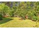 A well-maintained backyard showcasing a green lawn, framed by mature trees and landscaping at 1311 Antler Point Dr, Durham, NC 27713