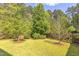 Landscaped backyard featuring a lush green lawn, mature trees, and a wood privacy fence at 1311 Antler Point Dr, Durham, NC 27713