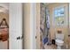 Bathroom including a toilet with a blue patterned shower curtain and a window view at 1317 Colonial Club Rd, Wake Forest, NC 27587