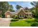 Brick two-story home featuring a side-entry garage, lush landscaping, and mature trees at 1317 Colonial Club Rd, Wake Forest, NC 27587