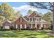 Beautiful brick home with manicured lawn, a porch with columns and lush green trees at 1317 Colonial Club Rd, Wake Forest, NC 27587