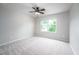 Well-lit bedroom featuring neutral carpet, a ceiling fan, and a large window at 15 White Spruce Ct, Durham, NC 27703