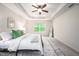 Bright bedroom featuring a tray ceiling, ceiling fan, neutral walls, and large window with green view at 15 White Spruce Ct, Durham, NC 27703