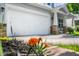 A ground-level shot shows a home's garage and porch from behind vibrant orange flowers at 15 White Spruce Ct, Durham, NC 27703