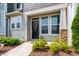 Charming townhouse entrance featuring a decorative wreath on the black door, surrounded by blooming flowers at 1820 Grassy Falls Ln, Wendell, NC 27591