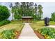 Concrete walking path lined with colorful flowers and greenery leading to a community pavilion at 1820 Grassy Falls Ln, Wendell, NC 27591
