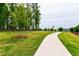 Manicured lawn alongside a concrete walking path, lined by trees and wooden fence, for a calm, natural setting at 1820 Grassy Falls Ln, Wendell, NC 27591