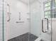 Modern shower features white tiled walls, shower shelves, glass door, and chrome grab bars at 203 Wood Cir, Chapel Hill, NC 27514