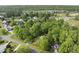 Aerial view of a home surrounded by trees, a planned community, green space, and recreational fields in the distance at 204 Black Forest Dr, Clayton, NC 27527