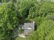 Aerial view of a charming home with a gray roof nestled in a lush green canopy of trees with a patio and well-maintained landscaping at 204 Black Forest Dr, Clayton, NC 27527