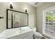 Bathroom features a large framed mirror over vanity, white toilet, and a window providing natural light at 204 Black Forest Dr, Clayton, NC 27527