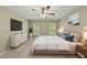Bright bedroom features a large bed, ceiling fan, dresser, wall-mounted TV, and natural light from the windows at 204 Black Forest Dr, Clayton, NC 27527