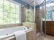 Bathroom with a soaking tub next to a large window and a glass-enclosed shower at 204 Flint Point Ln, Holly Springs, NC 27540