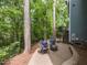Outdoor patio area with seating around a fire pit, surrounded by a wooded backyard at 204 Flint Point Ln, Holly Springs, NC 27540