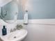 Powder room featuring a pedestal sink with white wainscoting and a round mirror at 204 Flint Point Ln, Holly Springs, NC 27540