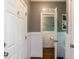 A hallway leads to a powder room featuring wainscoting, gray walls, and hardwood floors at 204 Flint Point Ln, Holly Springs, NC 27540