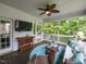 Relaxing screened porch with ceiling fan, TV, comfortable seating, and view of the wooded backyard at 204 Flint Point Ln, Holly Springs, NC 27540