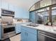 Well-lit kitchen featuring stainless steel appliances and blue cabinets with an adjacent outdoor area at 205 Wood Cir, Chapel Hill, NC 27514