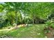 Serene backyard with green lawn, colorful chairs, mature shade trees, and a storage shed at 2128 Watkins St, Raleigh, NC 27604