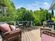 Outdoor deck with wicker furniture, colorful cushions, table, and gas grill overlooking lush greenery at 2128 Watkins St, Raleigh, NC 27604