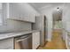 Galley kitchen featuring stainless steel appliances, white cabinets, and tiled backsplash at 2157 Dunn Rd, Raleigh, NC 27614