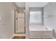 Well-lit bathroom showcasing a bathtub, shower and block window providing both style and privacy at 217 Carolina Town Ln, Holly Springs, NC 27540