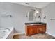 Bathroom featuring double vanity sinks with granite countertop and a soaking tub offering a spa-like experience at 217 Carolina Town Ln, Holly Springs, NC 27540
