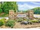 Stone community sign displaying Holly Glen amidst landscaped flowerbeds and lush trees at 217 Carolina Town Ln, Holly Springs, NC 27540