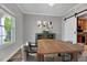 Dining room features wood floors, a modern chandelier, and barn door access to the kitchen at 217 Carolina Town Ln, Holly Springs, NC 27540