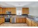 Well-equipped kitchen with stainless steel appliances, wood cabinets, and tile backsplash at 217 Carolina Town Ln, Holly Springs, NC 27540