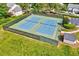 Aerial view of fenced tennis courts with blue surface surrounded by green lawns and trees at 217 Carolina Town Ln, Holly Springs, NC 27540
