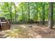 Backyard featuring a wood fence and a fire pit surrounded by lush trees at 2205 Long And Winding Rd, Raleigh, NC 27603