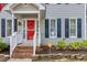 Close-up of the red front door, trimmed in white, complimented by the landscaping and dark shutters at 2205 Long And Winding Rd, Raleigh, NC 27603