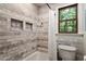 Bathroom with marble tile, built-in wall shelves, and a window for natural light at 224 Heidinger Dr, Cary, NC 27511