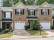 Charming townhouse with brick facade, black shutters, and single-car garage, surrounded by lush landscaping at 23 Great View Ct, Clayton, NC 27527