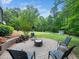 Backyard brick patio features a fire pit and seating area, surrounded by a lush lawn and mature trees at 2312 Laurelford Ln, Wake Forest, NC 27587
