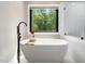 The relaxing bathroom features a modern soaking tub with matte black fixtures, bright window, and glass shower at 2312 Laurelford Ln, Wake Forest, NC 27587
