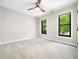 This neutral bedroom features soft carpet, a ceiling fan, and two windows offering bright views at 2312 Laurelford Ln, Wake Forest, NC 27587