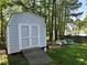 Backyard shed with double doors and ramp, nestled among trees and greenery providing extra storage at 2528 Beech Gap Ct, Raleigh, NC 27603
