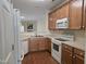 Kitchen with wood cabinets, white appliances, and view into the living room at 2565 Bent Green St, Raleigh, NC 27614