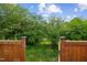 Wooden gate leading to a green, wooded area creates a sense of privacy and connection with nature at 270 Oak Park Blvd, Youngsville, NC 27596