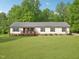 Charming single-story home with a well-manicured lawn, front porch, and a backdrop of lush green trees at 2705 Flat Rock Rd, Franklinton, NC 27525