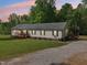 Single story home with a gravel driveway and covered porches nestled in a wooded yard at 2705 Flat Rock Rd, Franklinton, NC 27525