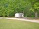 Metal outbuilding with a roll up door and neutral trim surrounded by a lush wooded lot at 2705 Flat Rock Rd, Franklinton, NC 27525