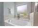 Bright bathroom with a luxurious soaking tub and frosted glass window offering natural light and privacy at 2728 Evanston Ave, Durham, NC 27703