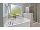 Relaxing bathroom with garden tub, frosted window, and separate glass shower stall at 2728 Evanston Ave, Durham, NC 27703