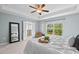 Comfortable main bedroom featuring a tray ceiling, ceiling fan, and a view of the trees at 2728 Evanston Ave, Durham, NC 27703