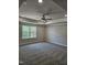 Primary bedroom with a tray ceiling, a ceiling fan, carpet floors, and a large window at 29 High Hampton Way, Fuquay Varina, NC 27526