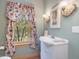 Bright bathroom featuring a white vanity, floral curtains, and decorative sconces at 3009 Pleasant Hill Church Rd, Siler City, NC 27344